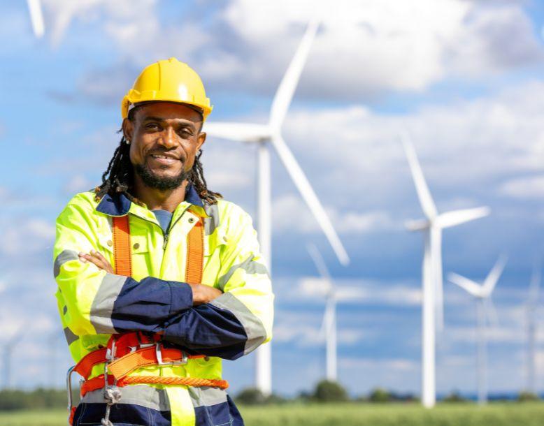 A utility worker stands in a field of wind turbines