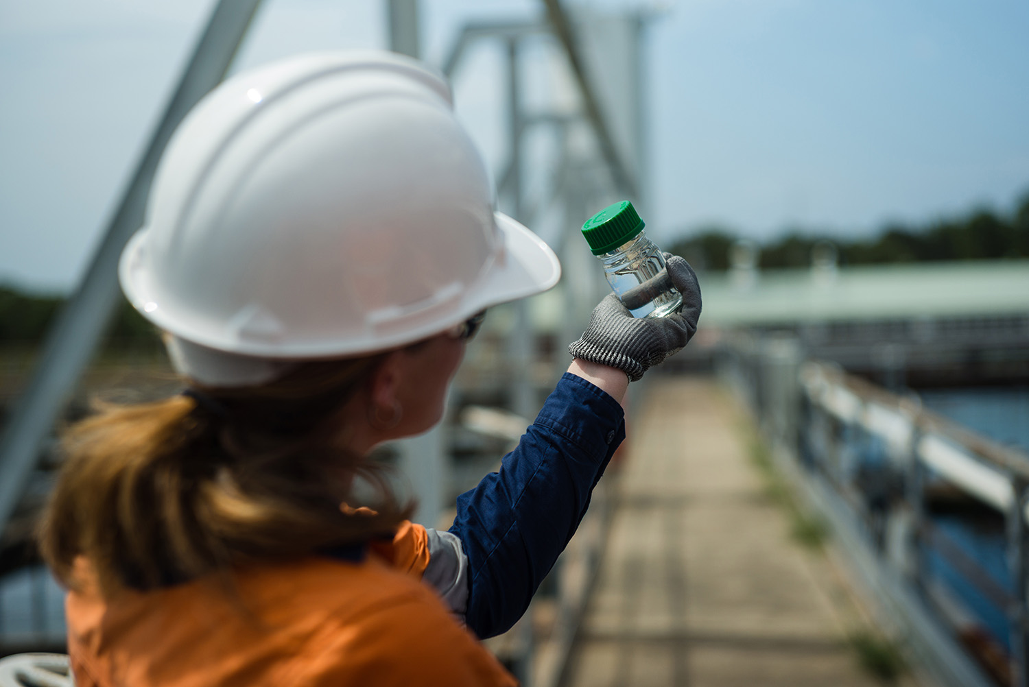 A Veolia employee holds a small vial of clear water up to inspect quality