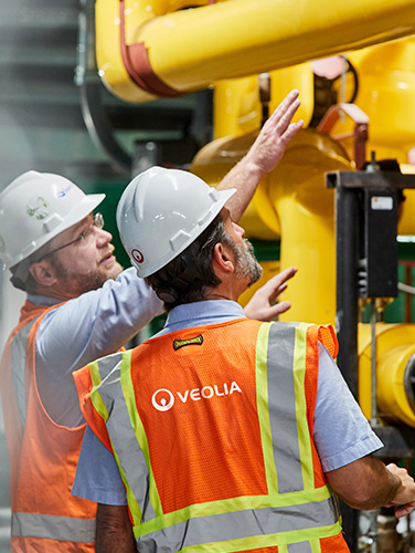 Two Veolia employees look at a building's utility infrastructure