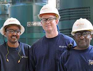 Three Veolia operators wearing hard hats, stand smiling