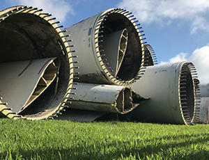 A pile of retired wind turbine blades sit on the grass