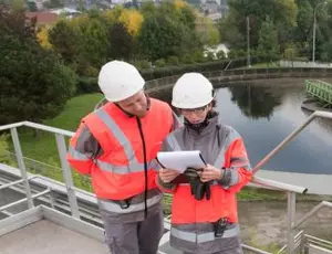 Two Veolia employees stand together at a wastewater treatment facility reviewing documents