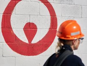 A Veolia employee walks by a Veolia logo painted on a white wall