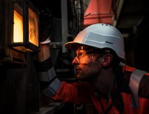 A Veolia employee looks through a sight glass into the incineration process