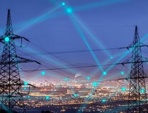 A set of electric transmission lines is seen in the foreground with a city in the background