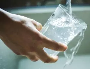person filling up glass of water
