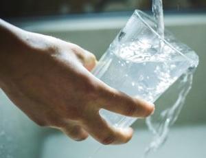 person filling up glass of water