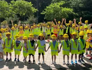 A group of school children wearing safety equipment stand holding hands in a circle