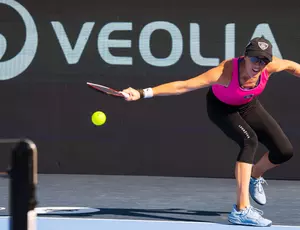 Pickleball Player Shown on court against Veolia branded side board 