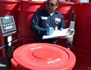 A Veolia employee measures a barrel of material
