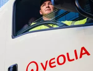 An employee looks out the window of a Veolia truck driving through the city