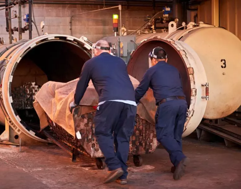 Two Veolia employees work together to load material into an autoclave