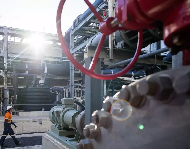 A close-up of industrial equipment as a person is seen walking by in the background