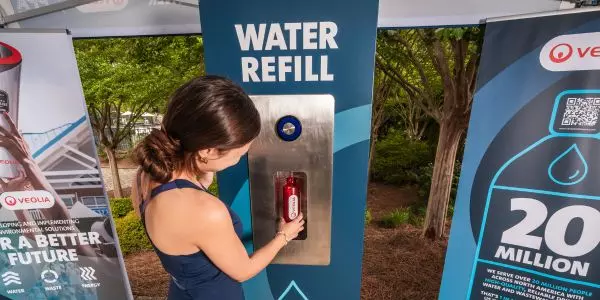 A pickleball fan fills her water bottle at a Veolia water refill station