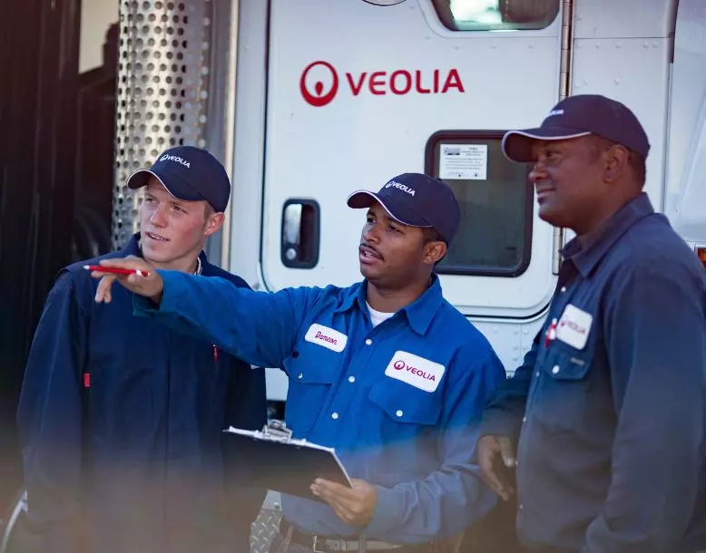 Three employees working with a Veolia truck in the background